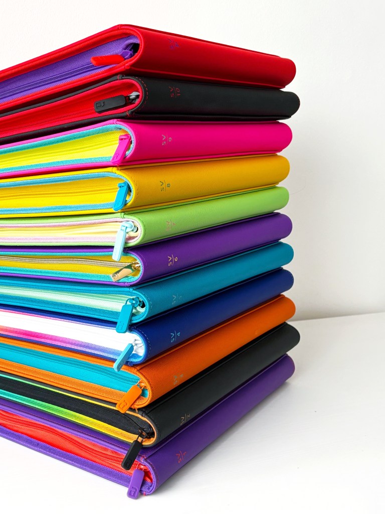 A stack of colorful Exo-Tec© binders inspired by the Scarlet & Violet era, featuring various colors and sizes with SV numbers on the spines.